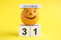 Pumpkin with halloween holiday calendar date against yellow background minimal creative concept.